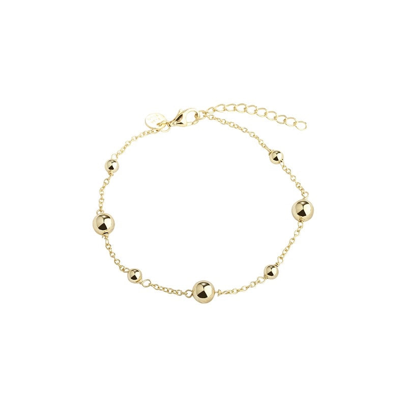 Alba armbånd i 14 karat forgyldt sterlingsølv med små kugler i forskellige størrelser fra Aqua Dulce, justerbar 17–20 cm.