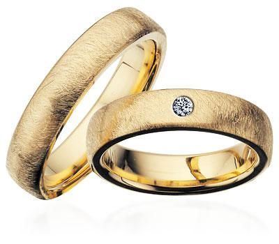 Scrouples vielsesringe i guld med frostet overflade og oval profil – liggende på flade