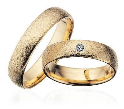 Scrouples vielsesringe i guld med rustik overflade – nærbillede af fatning med brillantslebet diamant
