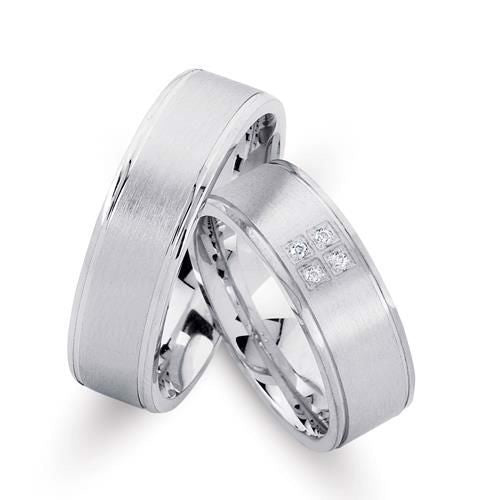 Smukke Nuran vielsesringe i rhodineret sølv med 4 syntetiske kubiske zirkonia og to graveringer – 6,5 mm bredde.
