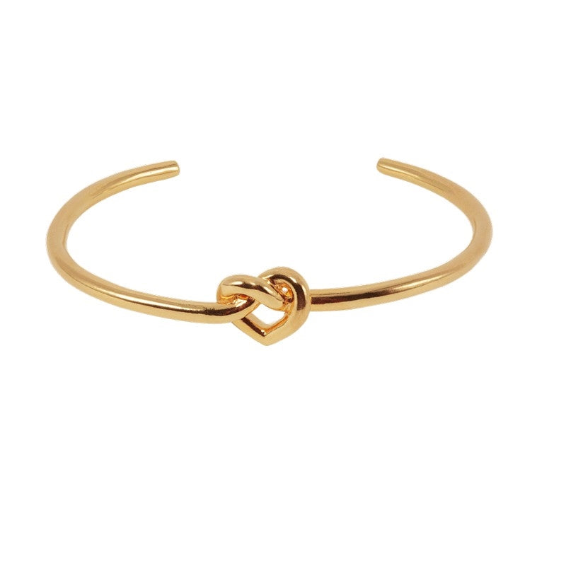 Jane Kønig Tied Heart armring i forgyldt sterlingsølv med åben bangle og hjerte.